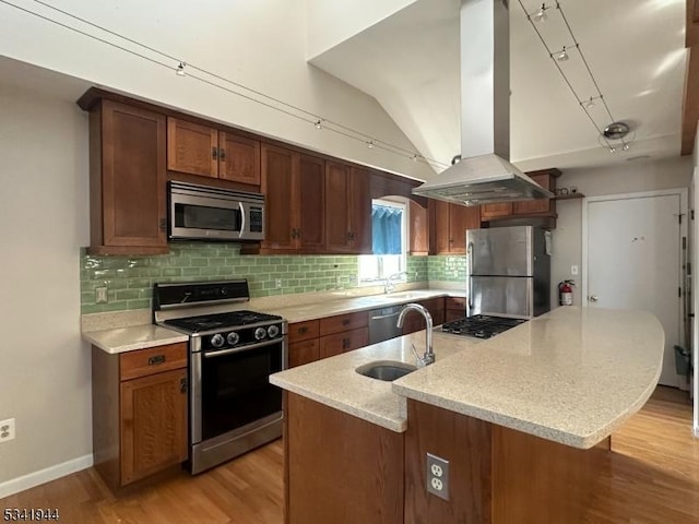 kitchen featuring a sink, stainless steel appliances, light wood-style floors, island range hood, and decorative backsplash