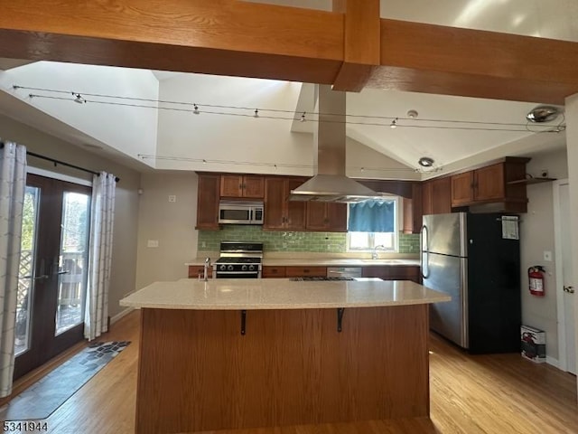 kitchen featuring decorative backsplash, light wood finished floors, island exhaust hood, and appliances with stainless steel finishes