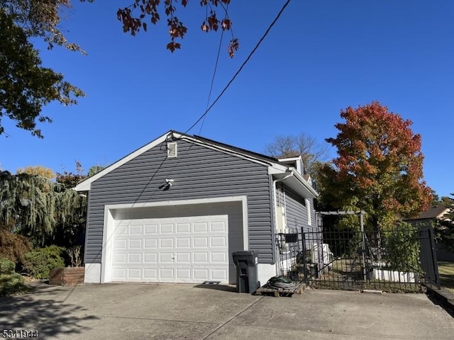 view of side of property featuring a garage, driveway, and fence