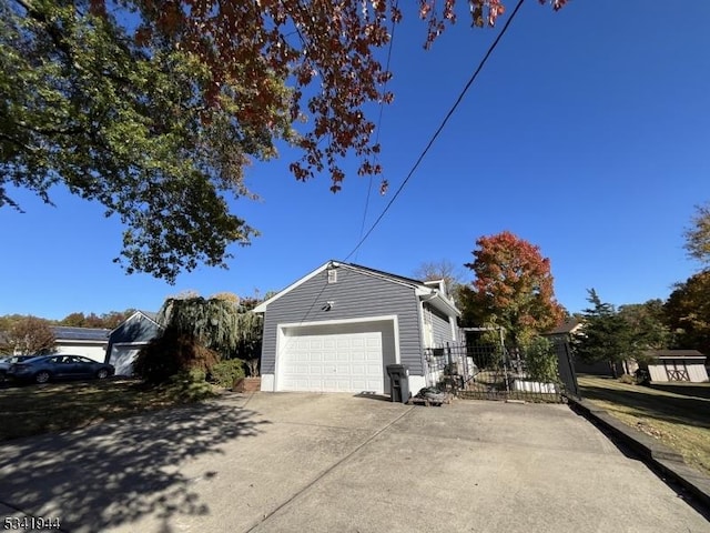 view of property exterior featuring an attached garage, driveway, and fence