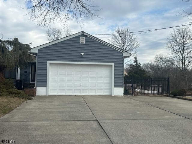 garage featuring concrete driveway and fence