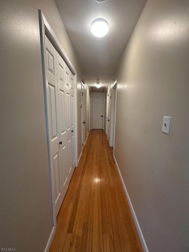 hallway with attic access, wood finished floors, and baseboards