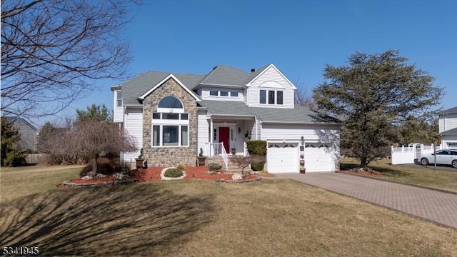 view of front of home featuring a front yard, decorative driveway, stone siding, and an attached garage