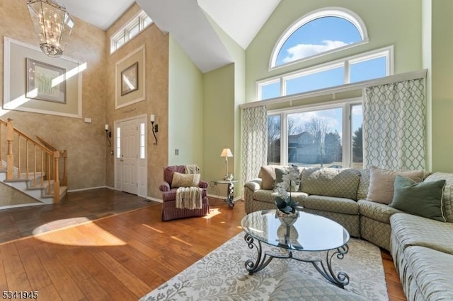 living area with high vaulted ceiling, wood finished floors, and a healthy amount of sunlight