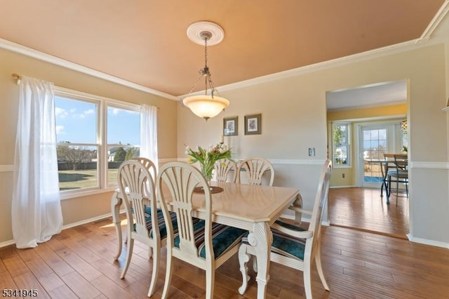 dining room featuring baseboards, hardwood / wood-style floors, and crown molding