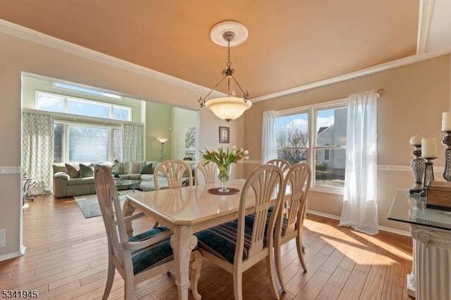 dining area with a wealth of natural light, light wood-style floors, and crown molding