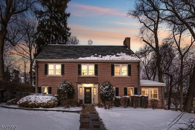 colonial home featuring brick siding and a chimney