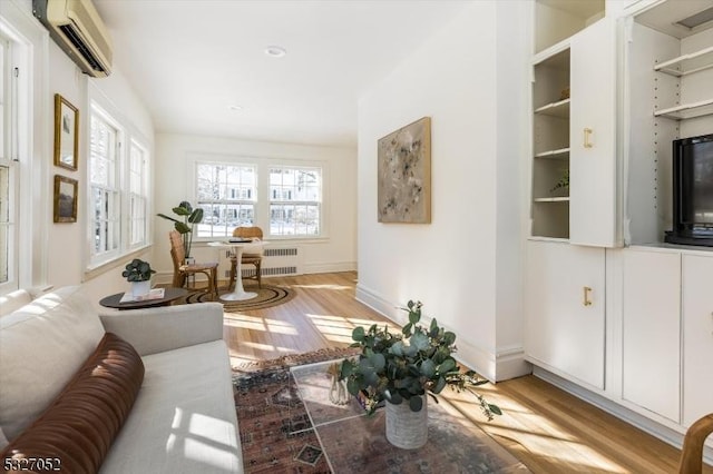 living room featuring radiator, a wall mounted air conditioner, light wood-type flooring, and baseboards