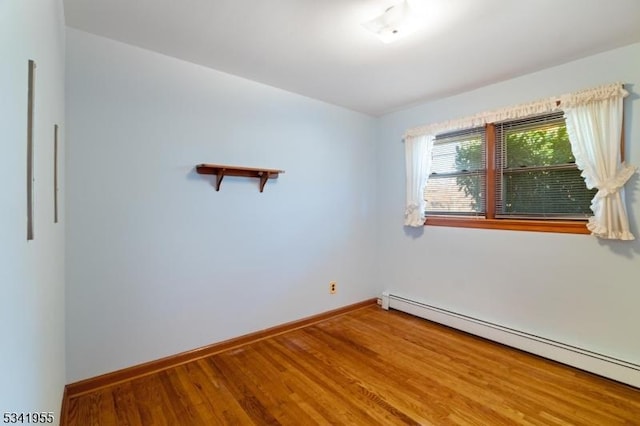 spare room with baseboard heating, baseboards, and wood finished floors