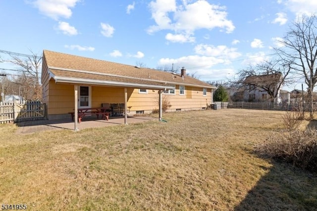 back of house featuring a shingled roof, a patio area, fence, and a lawn