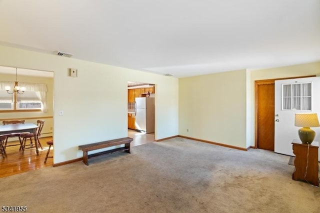 living area with baseboards, visible vents, a chandelier, and light carpet