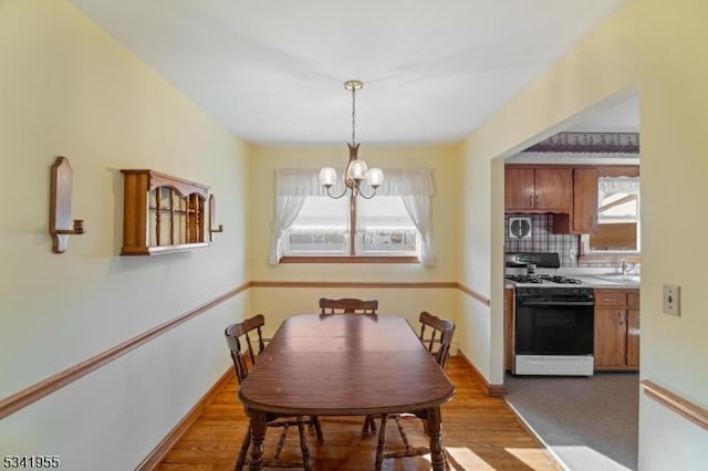 dining area with baseboards, wood finished floors, and a chandelier