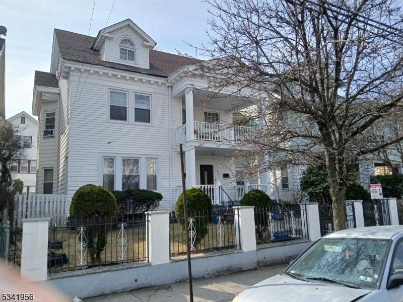 neoclassical / greek revival house featuring a balcony and a fenced front yard