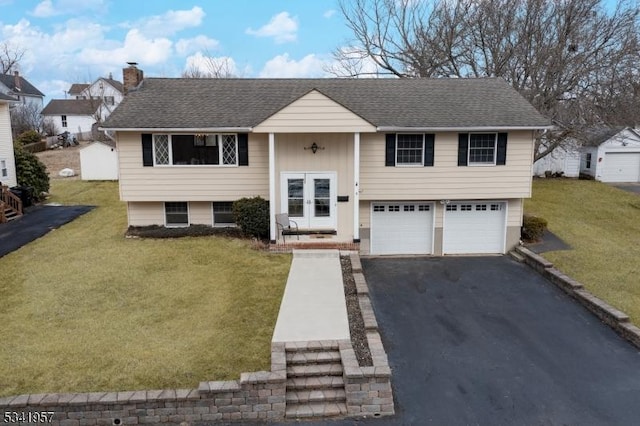 bi-level home with french doors, a front yard, a chimney, and aphalt driveway