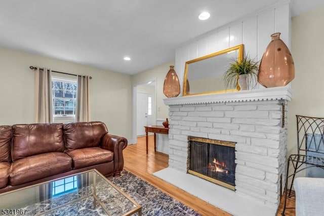 living room featuring a brick fireplace, wood finished floors, and recessed lighting