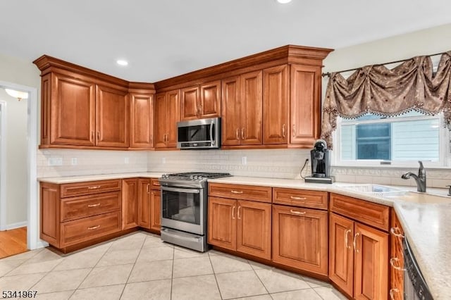 kitchen with stainless steel appliances, brown cabinetry, a sink, and backsplash