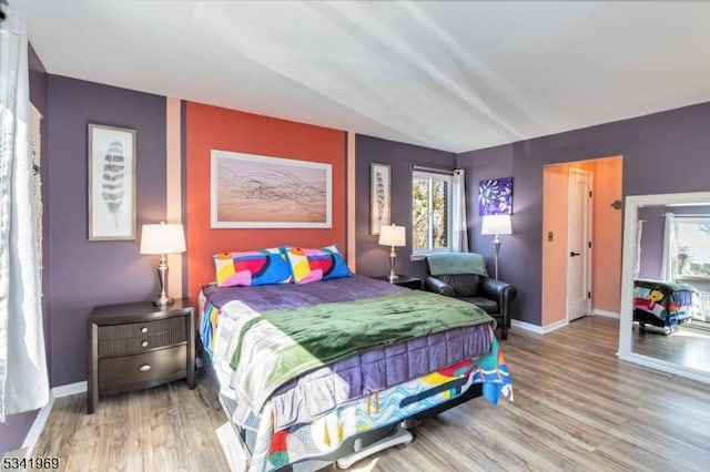 bedroom featuring multiple windows, baseboards, and wood finished floors