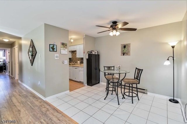 dining space with a baseboard heating unit, light tile patterned floors, a ceiling fan, and baseboards