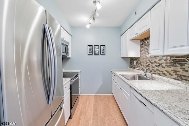 kitchen featuring a sink, white cabinets, appliances with stainless steel finishes, backsplash, and light wood finished floors