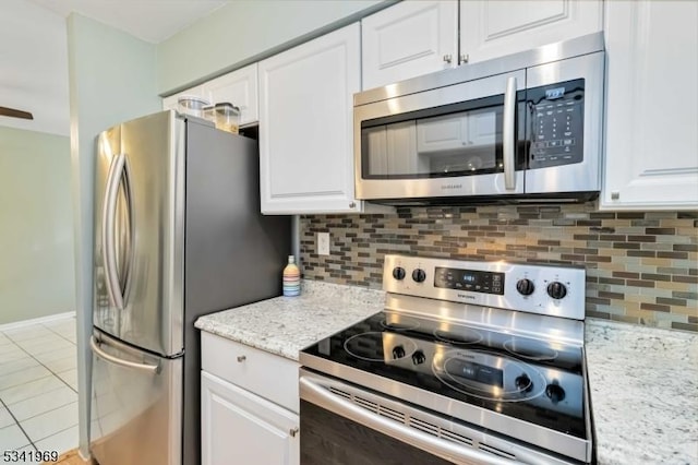 kitchen featuring light tile patterned floors, decorative backsplash, light stone countertops, stainless steel appliances, and white cabinetry