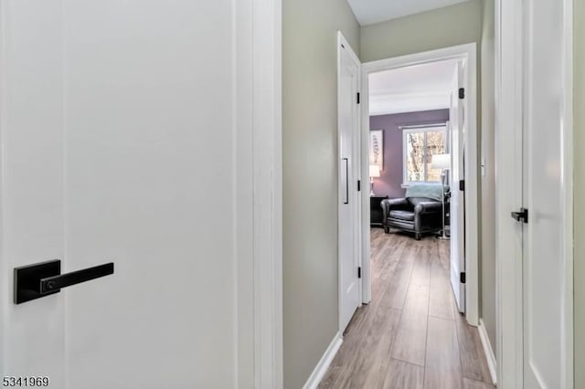 hallway with light wood-type flooring and baseboards