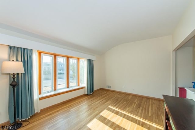 interior space with light wood-style floors, lofted ceiling, visible vents, and baseboards