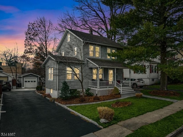 view of front of home with aphalt driveway, a porch, a chimney, an outdoor structure, and a detached garage