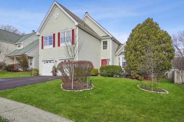 view of front facade with a garage, fence, aphalt driveway, and a front yard