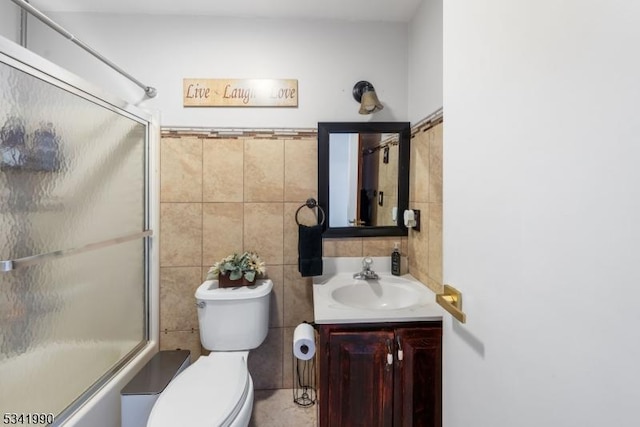 full bath with toilet, enclosed tub / shower combo, vanity, and tile walls