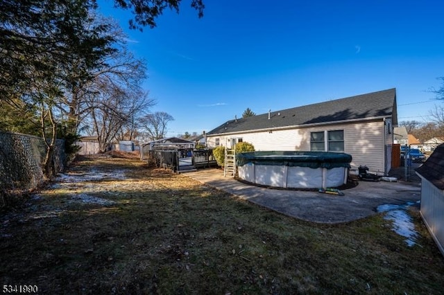 back of house featuring a deck, a fenced backyard, and a covered pool