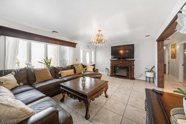 living area with light tile patterned flooring, a notable chandelier, visible vents, baseboards, and a glass covered fireplace