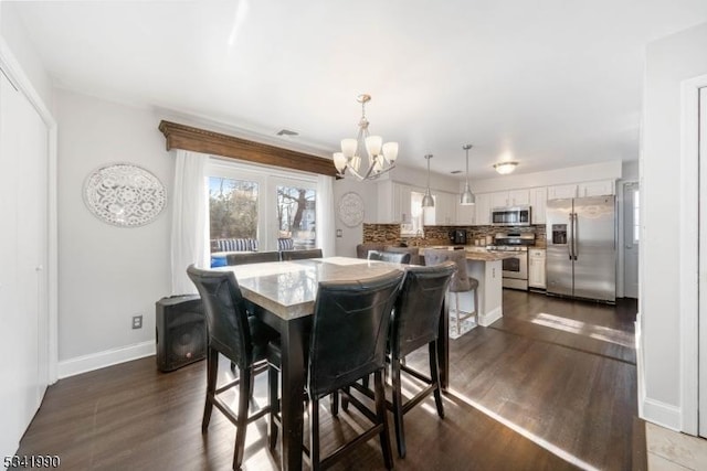 dining room with baseboards, visible vents, a chandelier, and dark wood finished floors