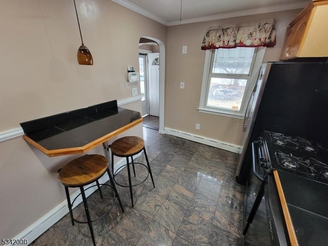 kitchen featuring arched walkways, baseboards, baseboard heating, black range with gas stovetop, and crown molding