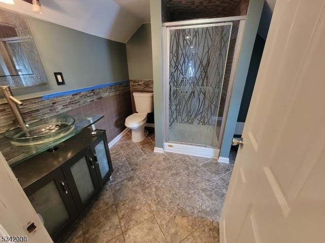 bathroom featuring toilet, a stall shower, tile walls, and vanity