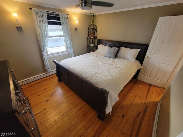 bedroom with ornamental molding, baseboard heating, and wood-type flooring