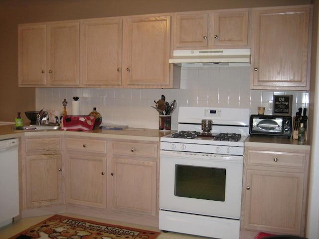 kitchen featuring under cabinet range hood, light brown cabinets, white appliances, and a sink