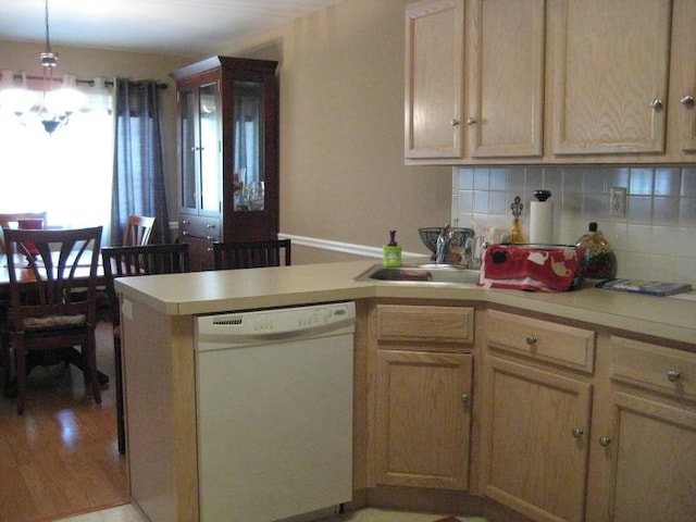 kitchen featuring decorative backsplash, dishwasher, a peninsula, light countertops, and a sink