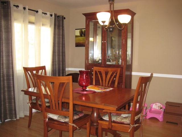 dining room with wood finished floors and an inviting chandelier