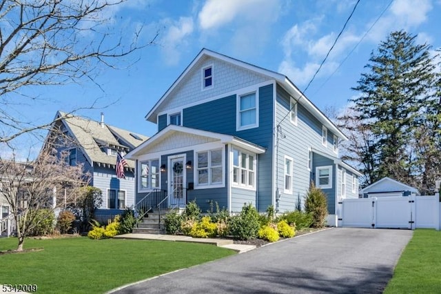 traditional style home featuring a gate, a detached garage, and a front lawn