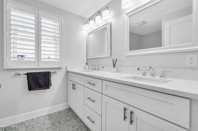 bathroom with visible vents, a sink, baseboards, and double vanity