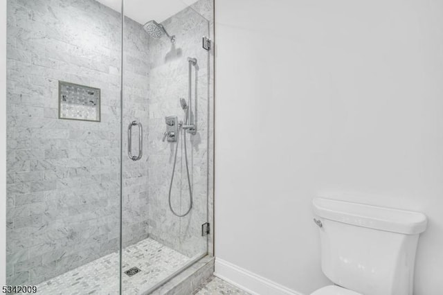 full bath featuring toilet, a stall shower, and baseboards