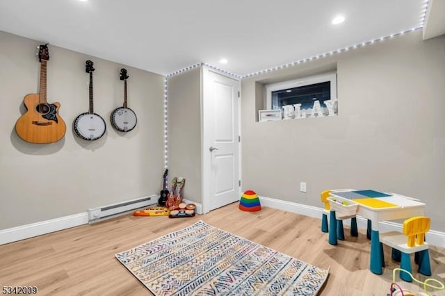 recreation room featuring baseboard heating, recessed lighting, wood finished floors, and baseboards