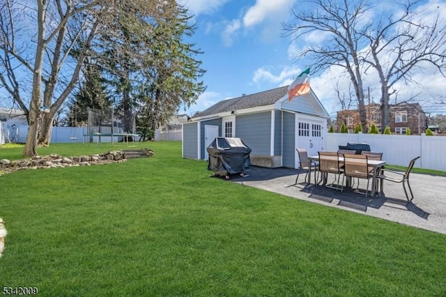 view of yard featuring a patio area, a trampoline, an outdoor structure, and a fenced backyard