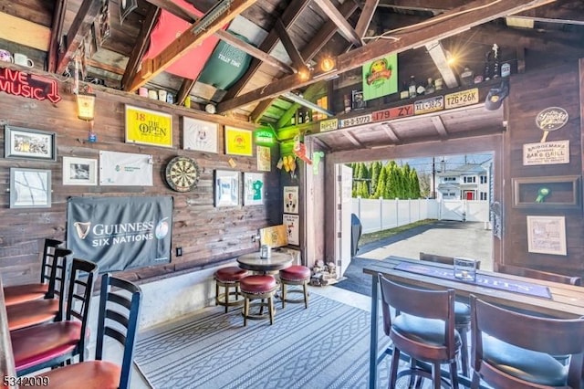 interior space with vaulted ceiling with beams and wooden walls