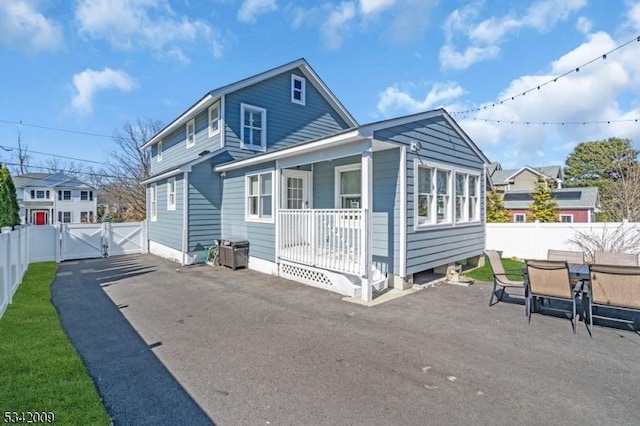 back of house with a gate, a fenced backyard, and a patio