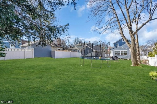 view of yard with a trampoline and a fenced backyard