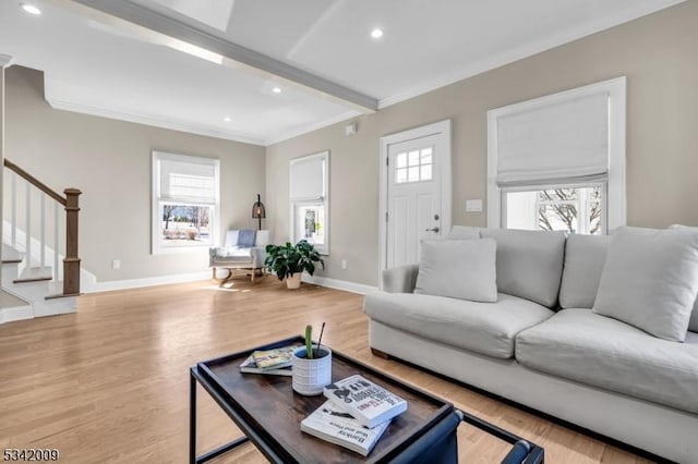 living room featuring a wealth of natural light, crown molding, stairway, and wood finished floors