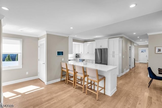 kitchen with high quality fridge, a kitchen breakfast bar, white cabinets, light countertops, and backsplash