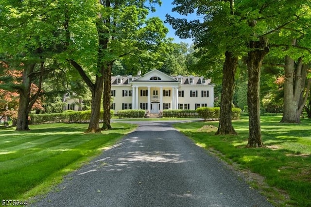 greek revival inspired property featuring a front lawn and gravel driveway