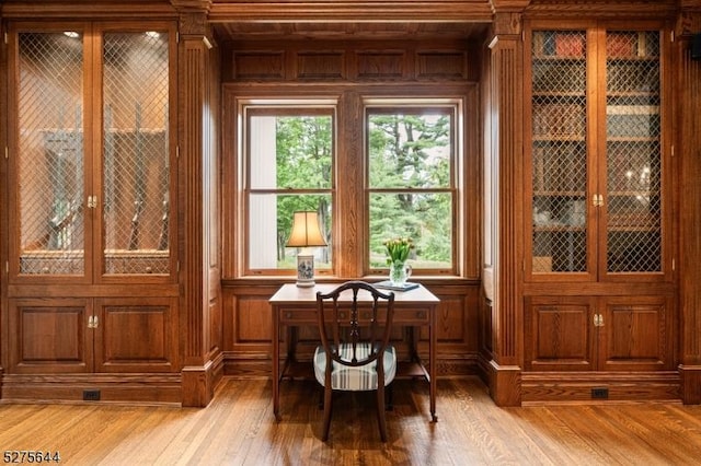 home office featuring light wood-type flooring and wood walls